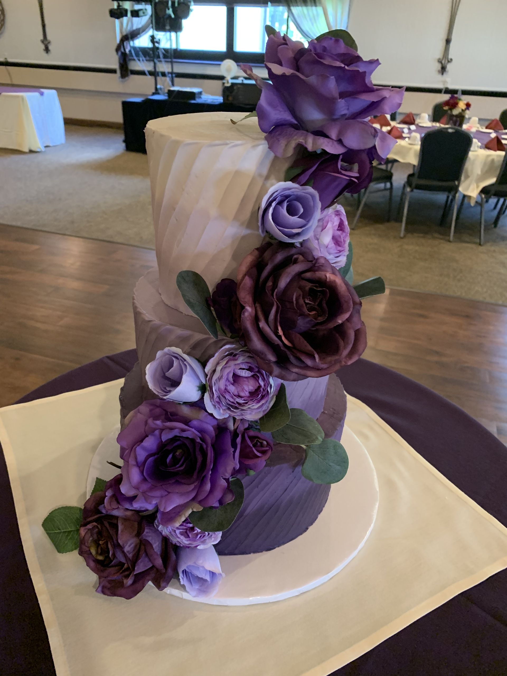 a wedding cake with purple flowers on it is on a table .