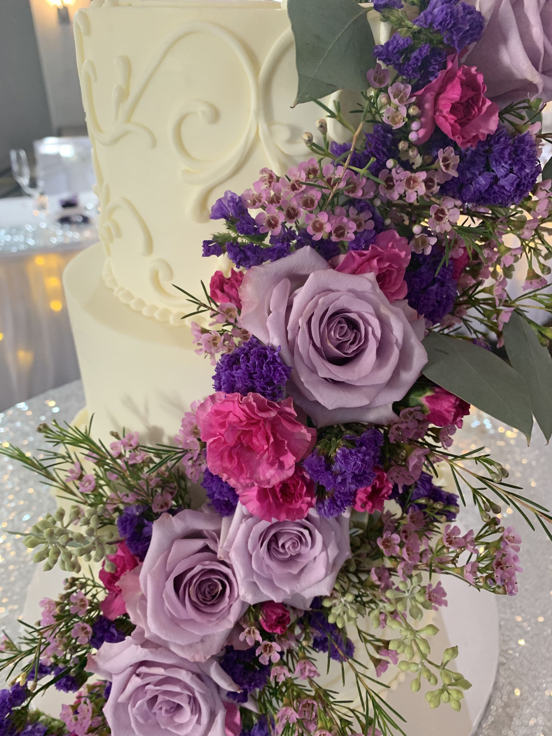 a wedding cake with purple and pink flowers on top of it .