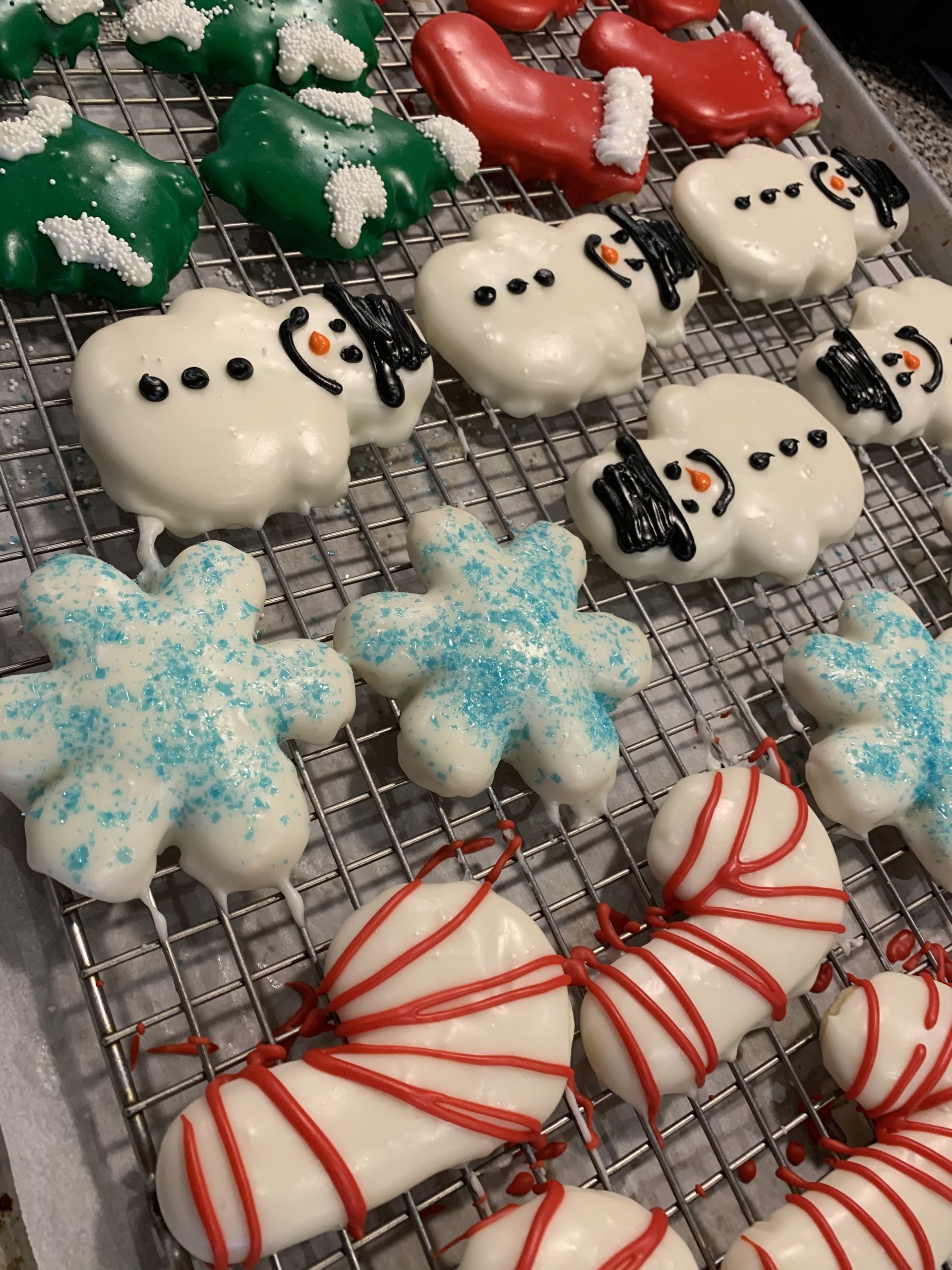 a bunch of christmas cookies are sitting on a cooling rack .