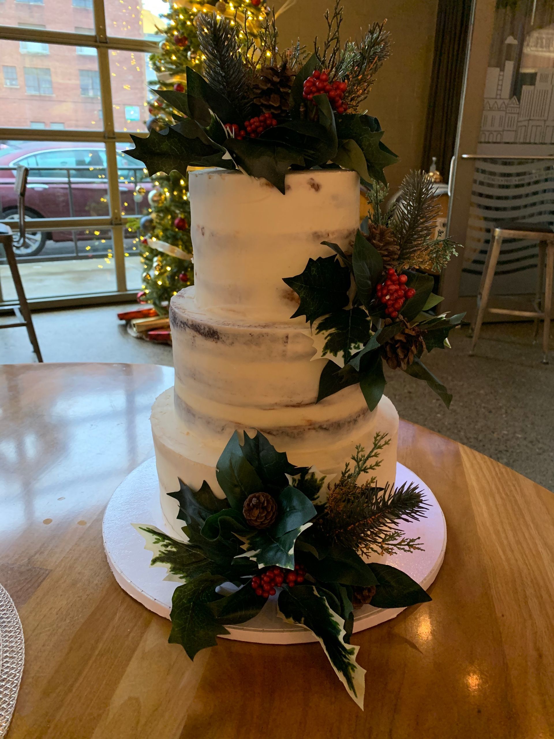 a wedding cake is sitting on a wooden table in front of a christmas tree .