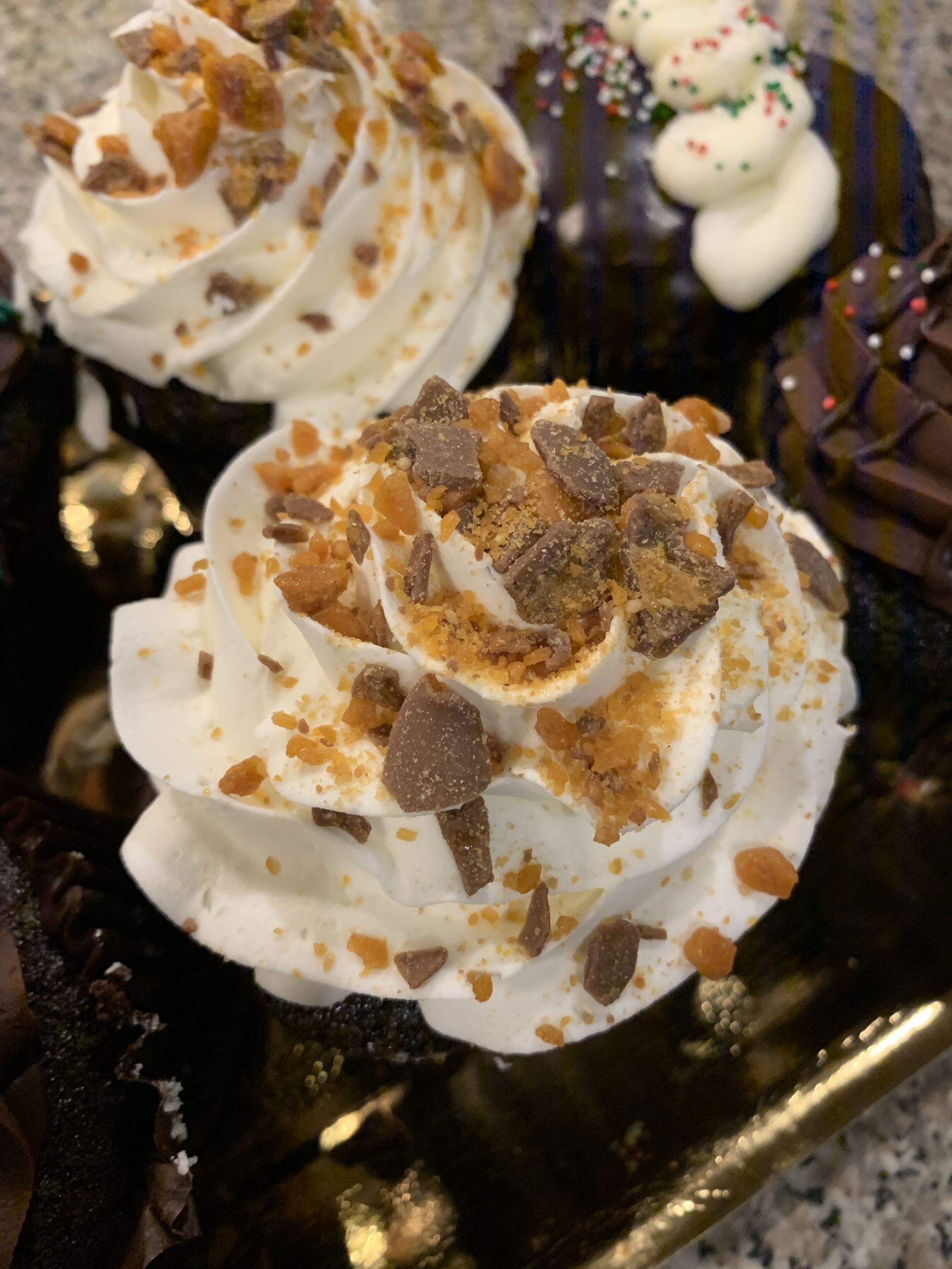 a close up of a cupcake with whipped cream and chocolate chips on top .