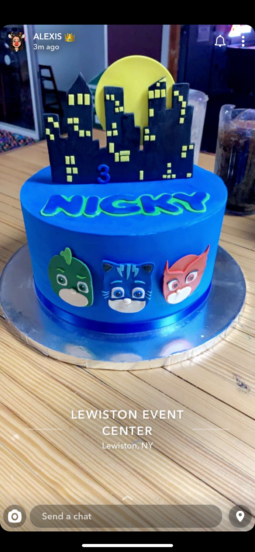 a blue cake with pj masks on it is on a wooden table .
