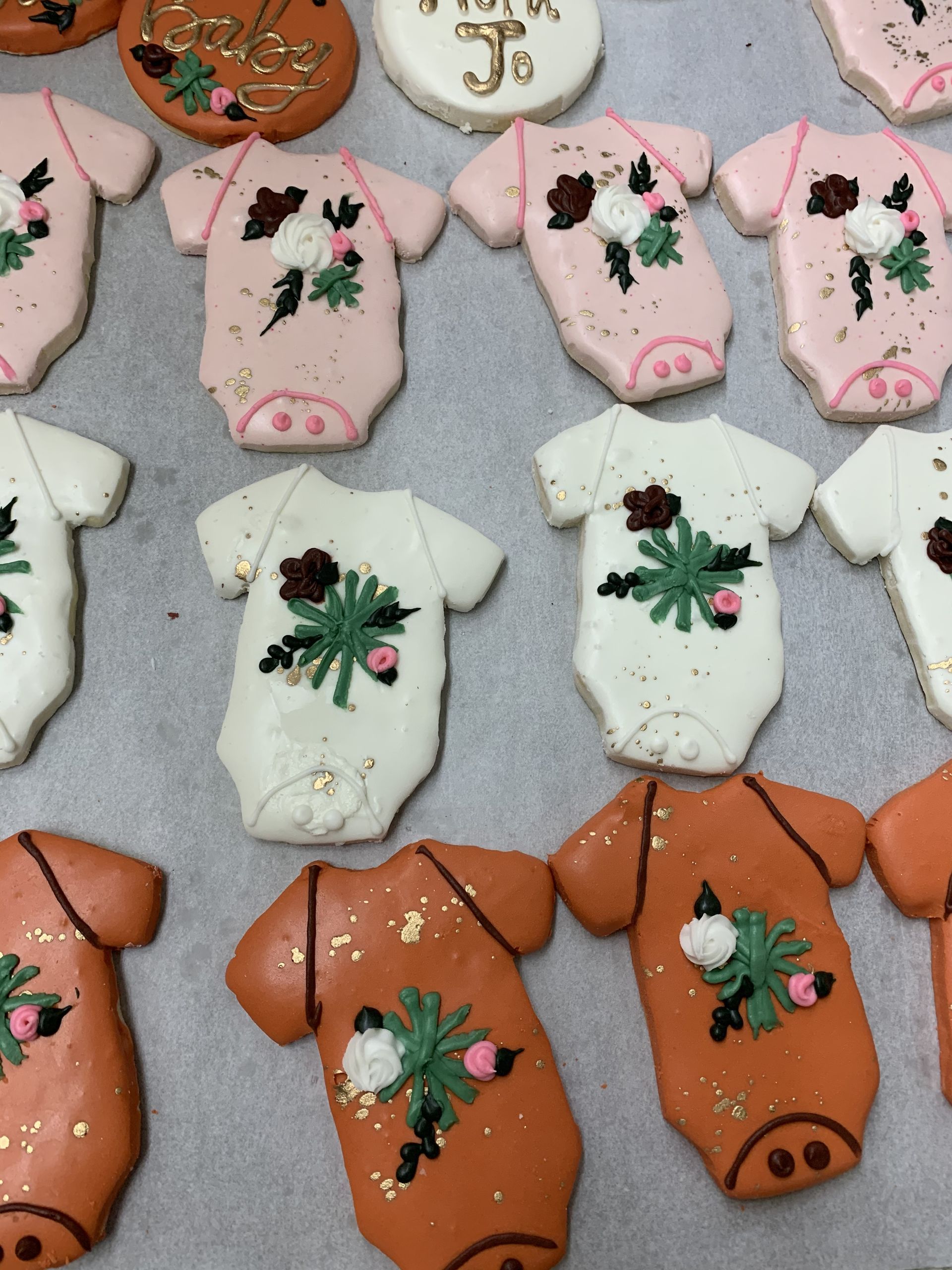 a bunch of baby onesie cookies with flowers on them