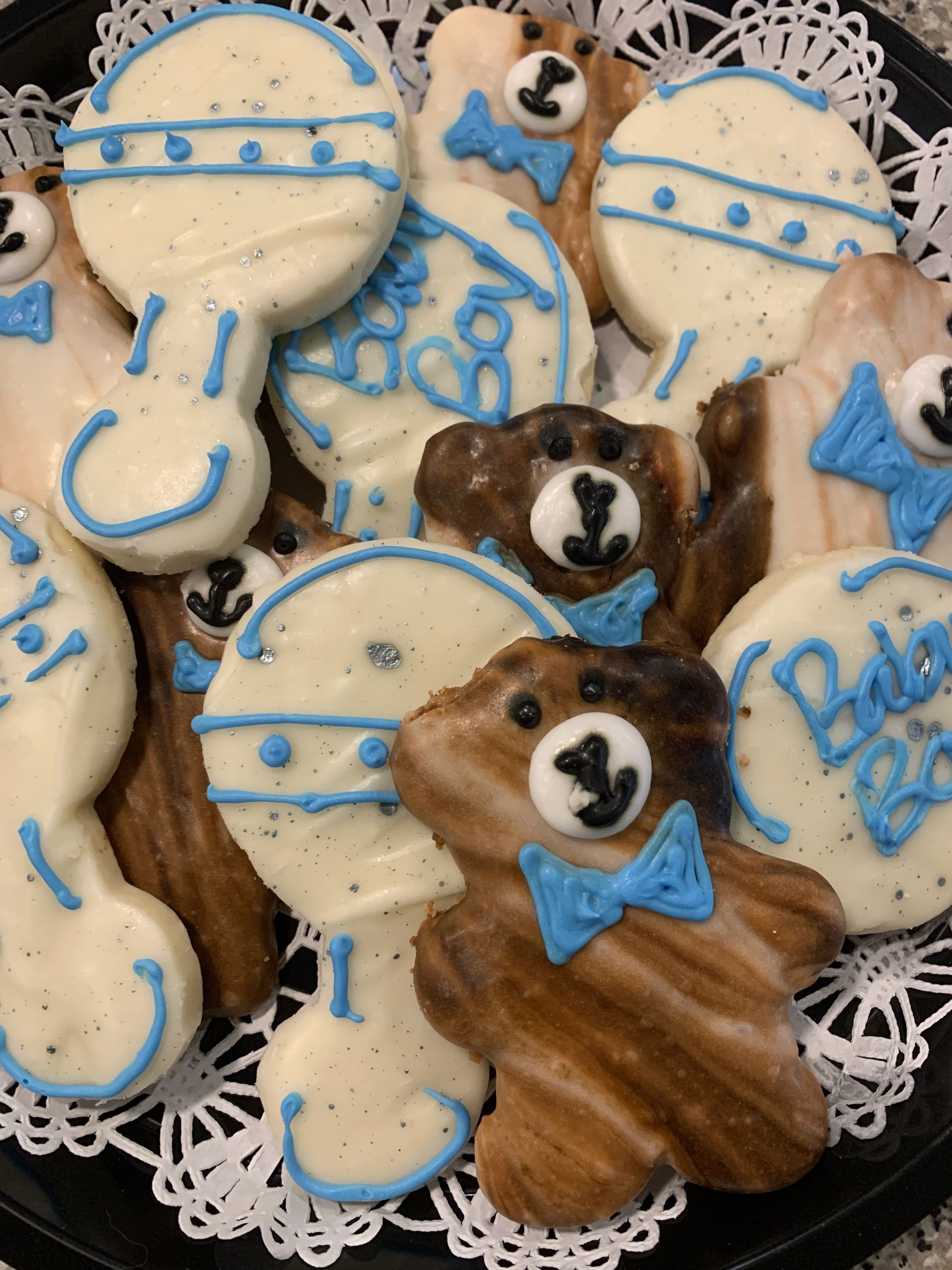 a black plate topped with a variety of baby shower cookies