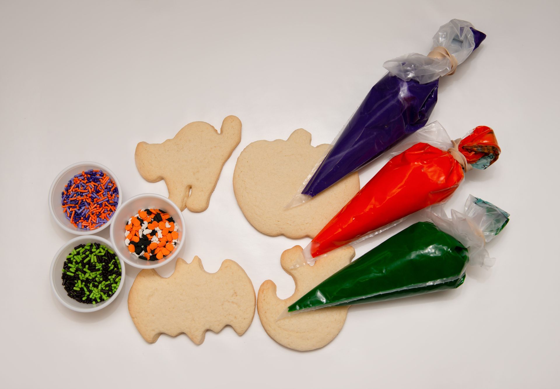 a set of halloween cookies with icing and sprinkles on a table .