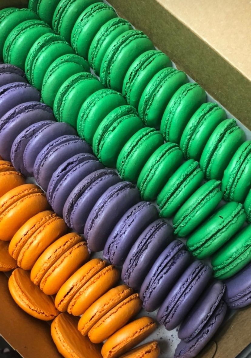 a box filled with green purple and orange macarons