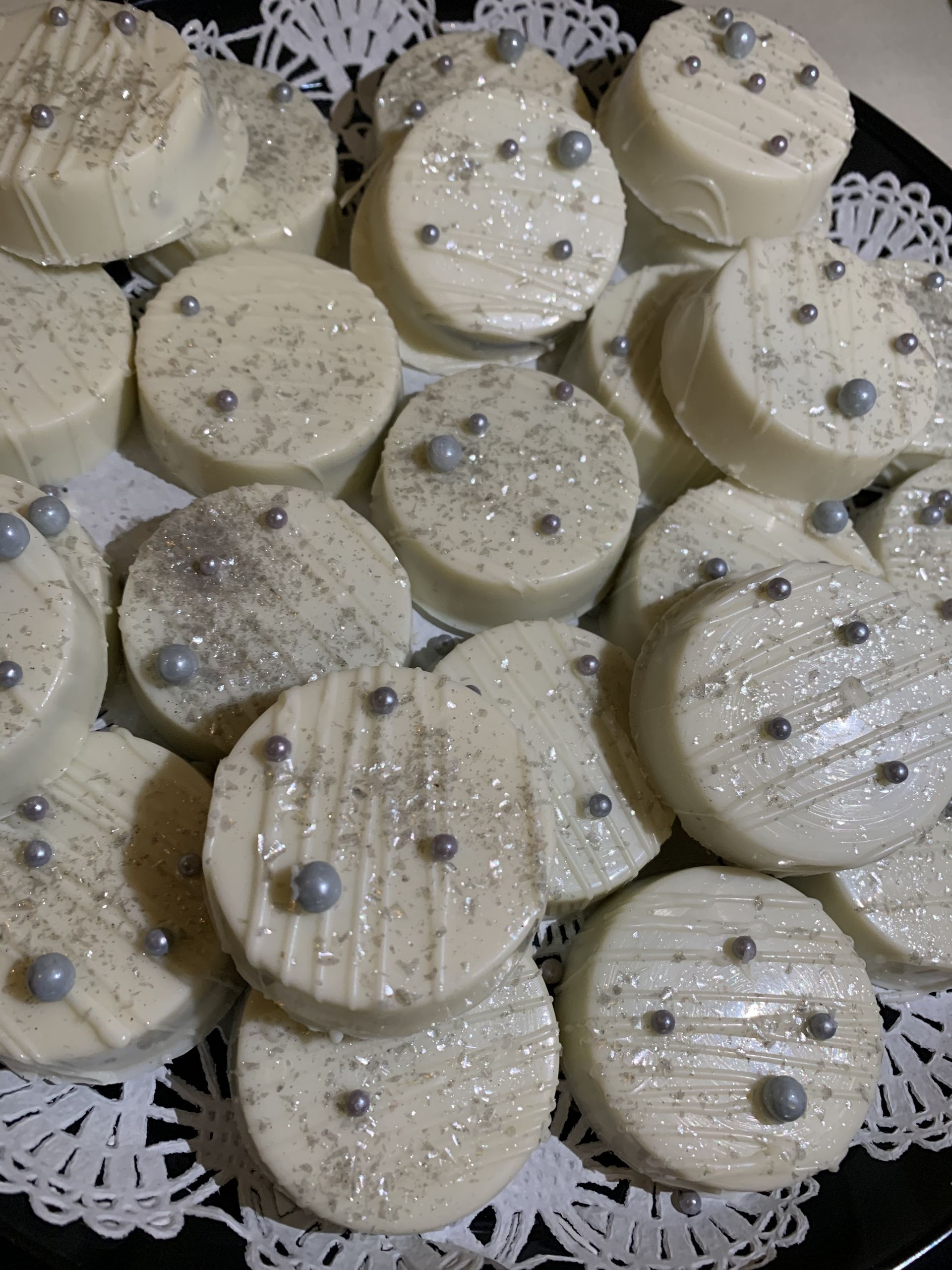 a plate of white cookies with silver sprinkles on them .