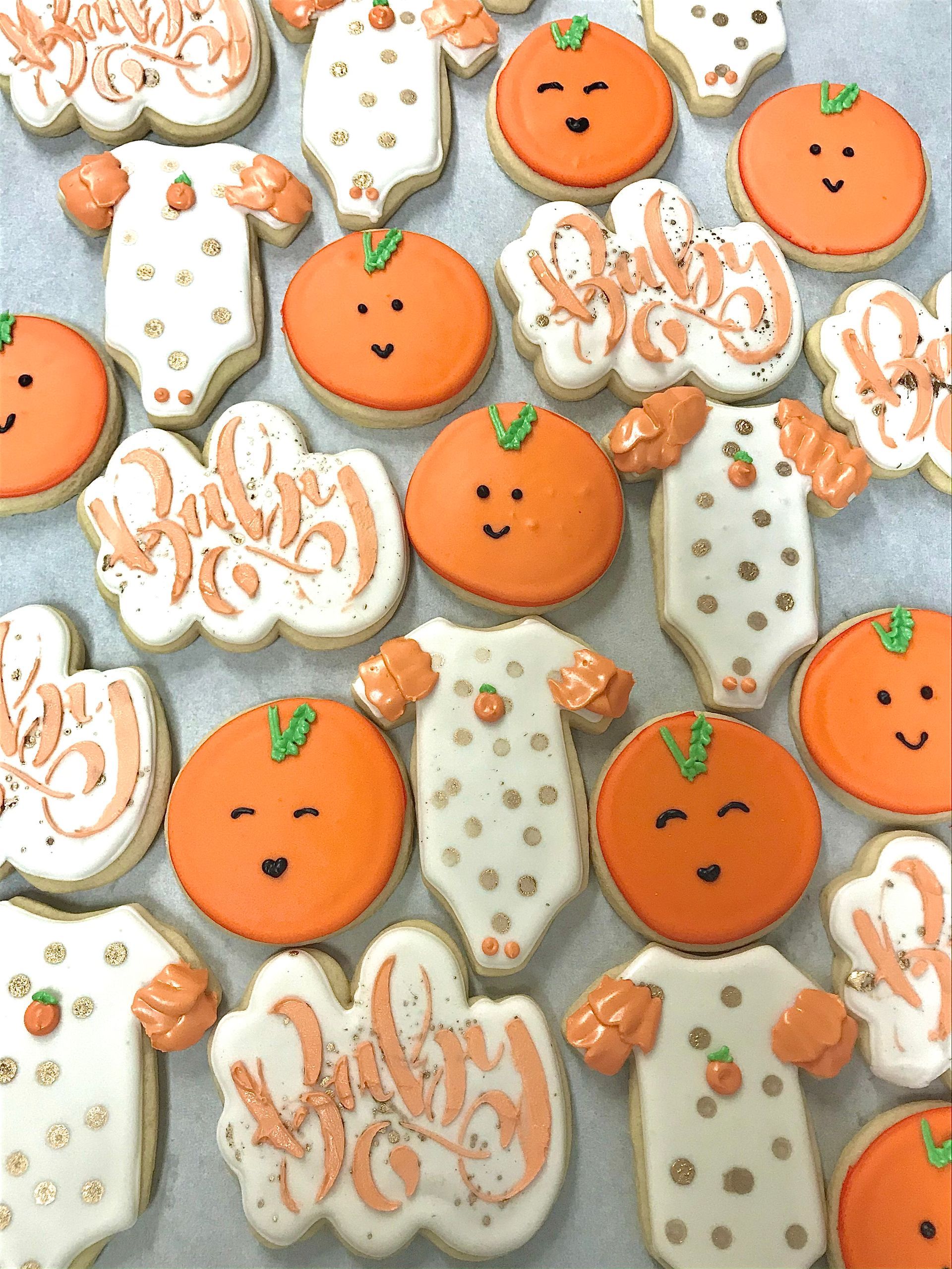 a bunch of orange and white baby shower cookies