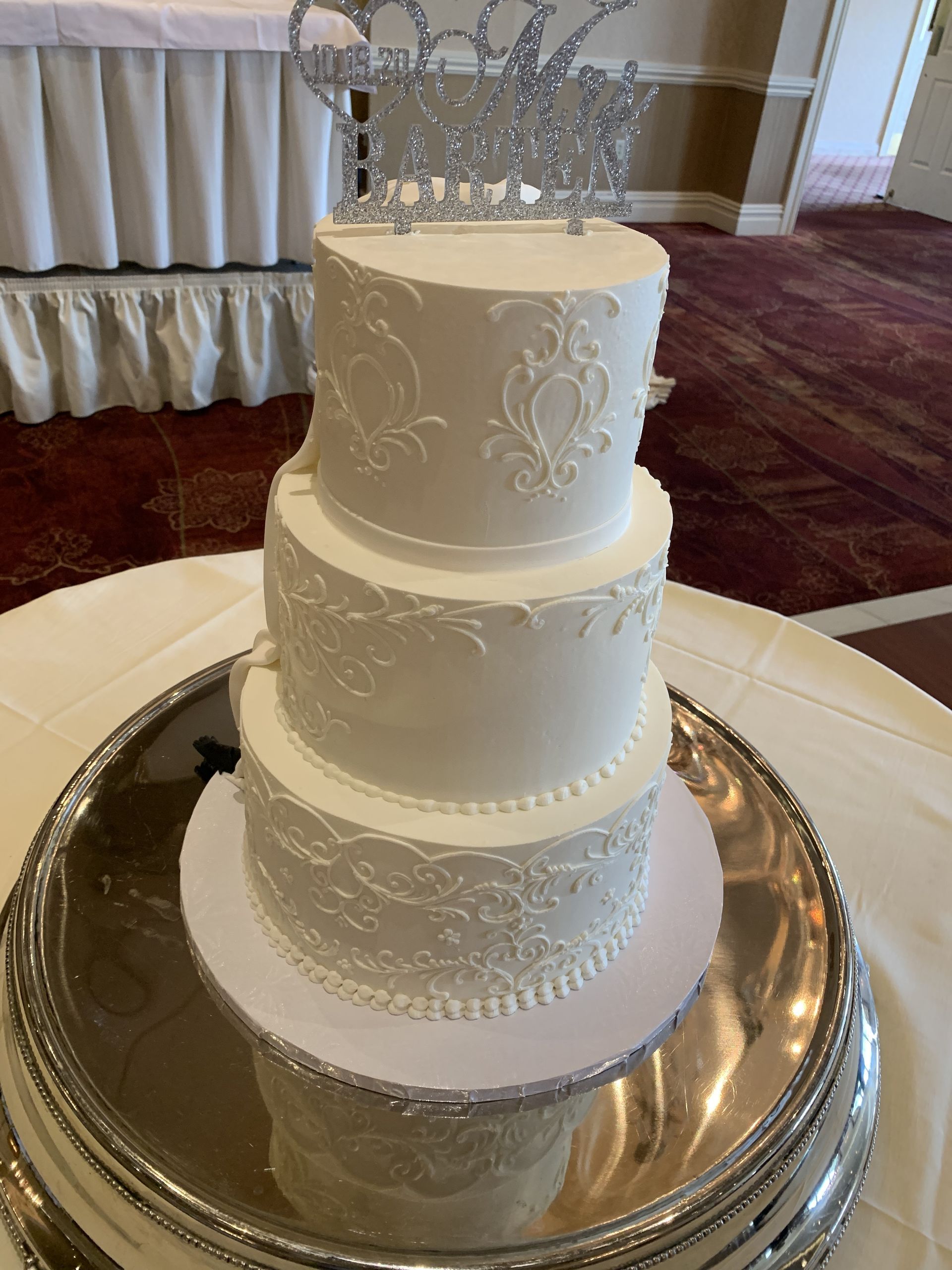 a white wedding cake is sitting on top of a silver plate on a table .