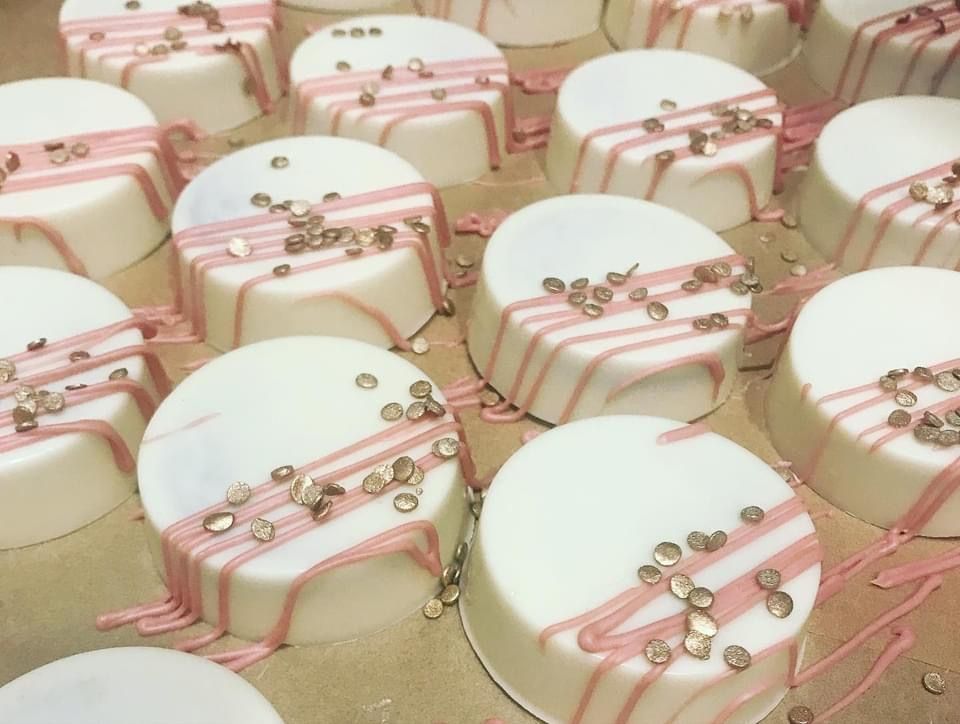 a bunch of white cakes with pink frosting and sprinkles