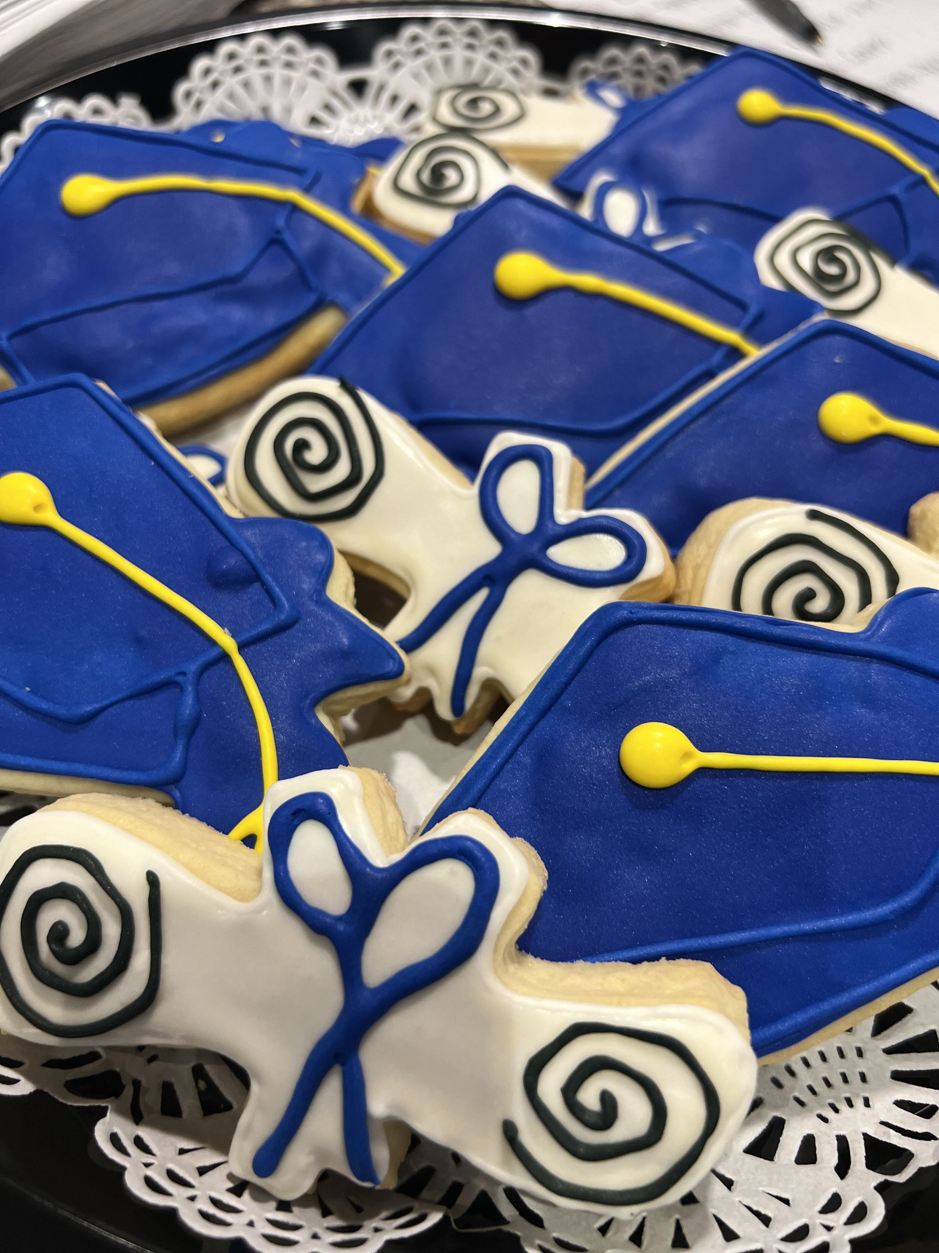 a tray of blue and white graduation cap and gown cookies