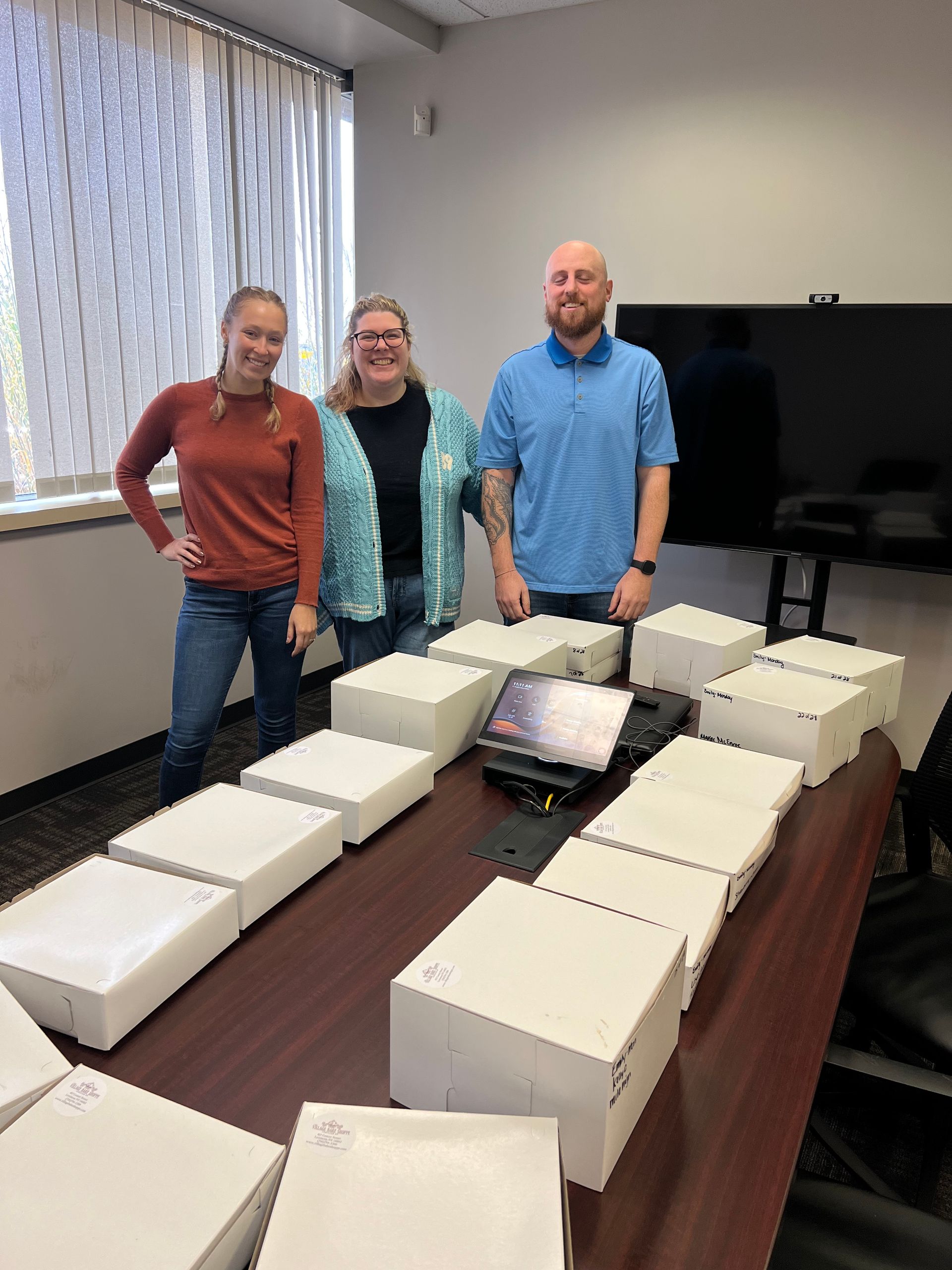 three people are standing around a table with boxes on it .