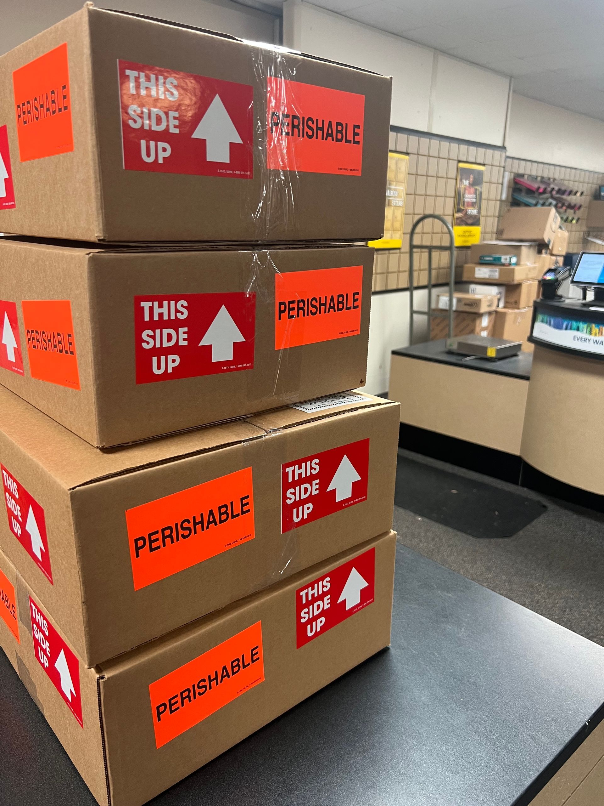 a stack of cardboard boxes with perishable stickers on them