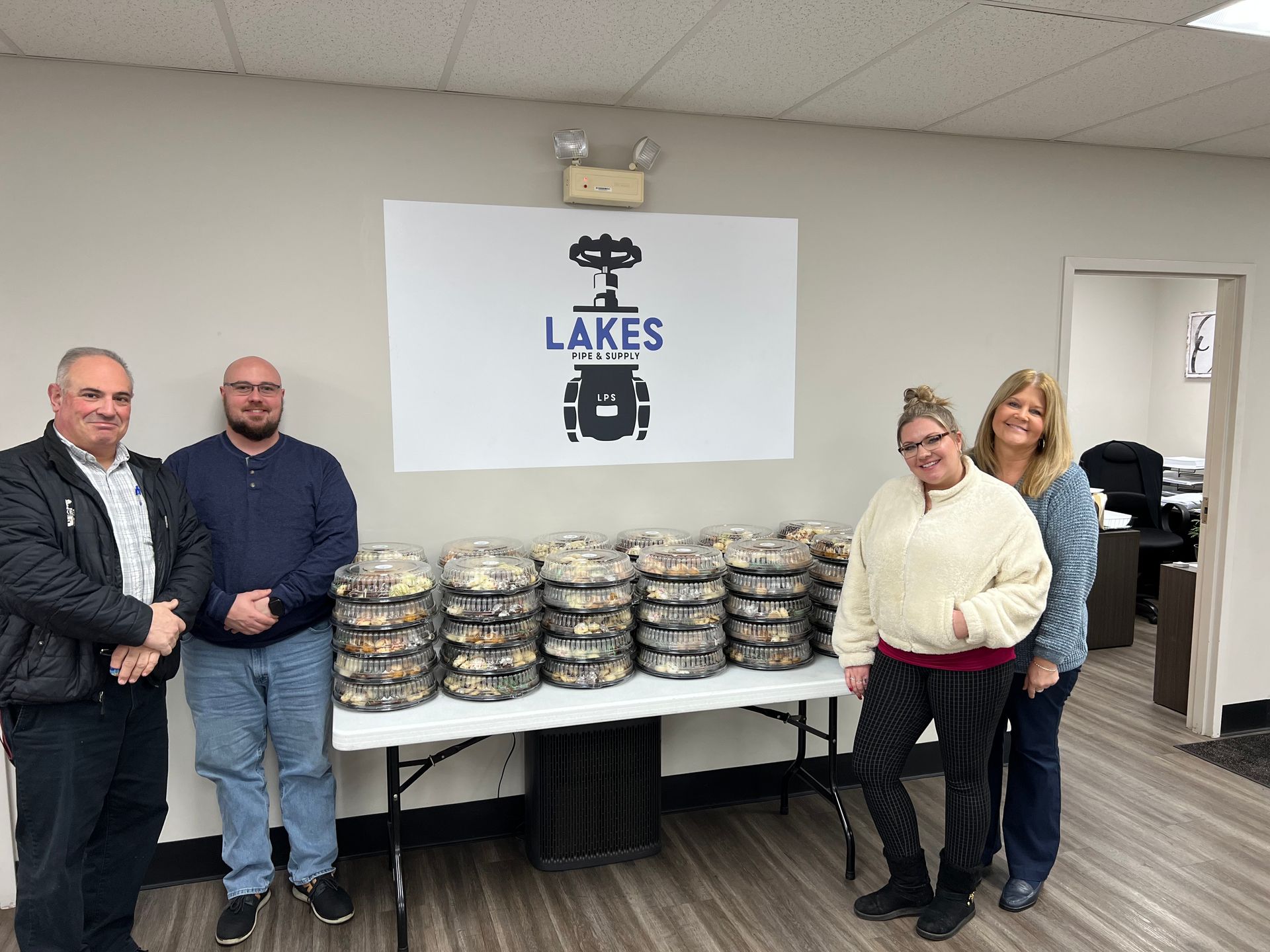 a group of people are standing in front of a table full of food .