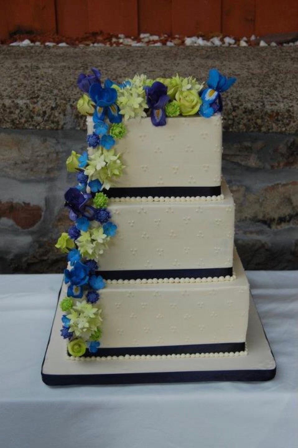 a wedding cake with blue and green flowers on it