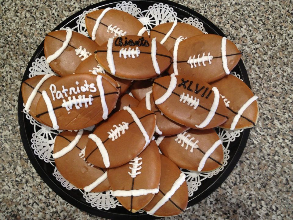 a plate of football cookies with patriots written on them