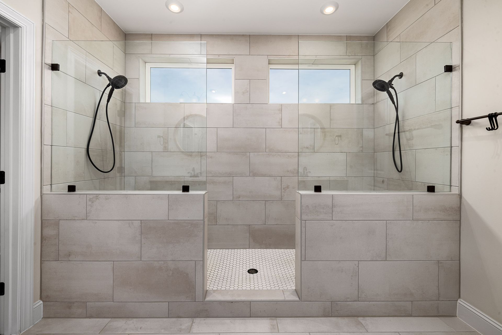 Modern bathroom with walk-in shower, beige tile walls, glass panels, and dual showerheads