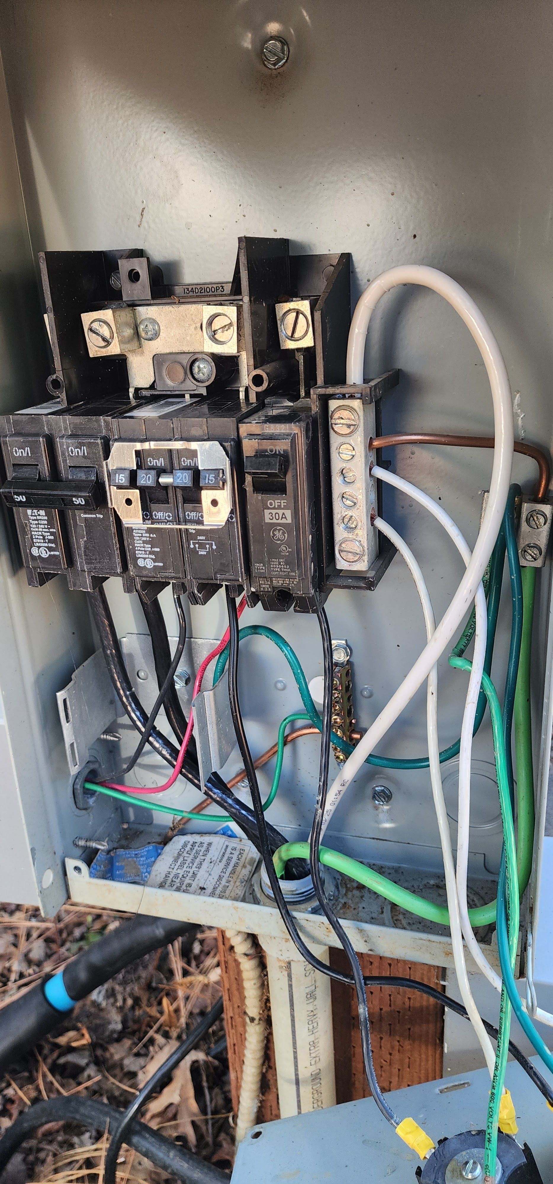 Open outdoor electrical service panel showing breakers and wiring connections mounted on a wooden post.
