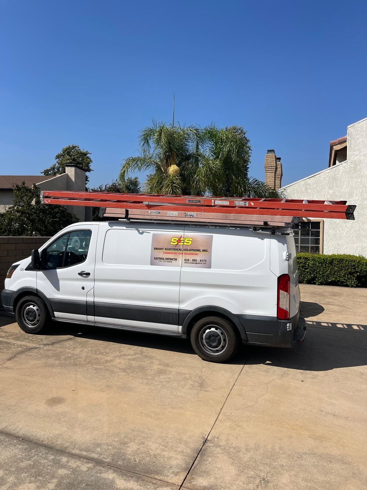 Open van packed with tools, ladders, cables, and red storage cases in the cargo area.