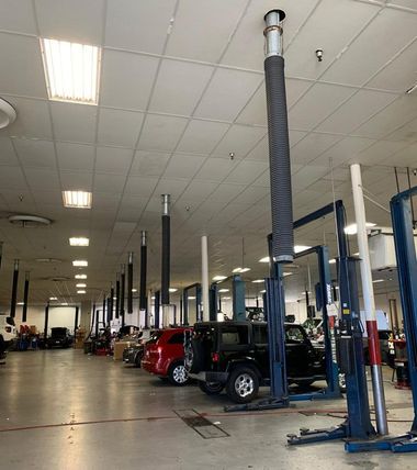 Auto repair shop interior with car lifts, parked vehicles, and a high ceiling