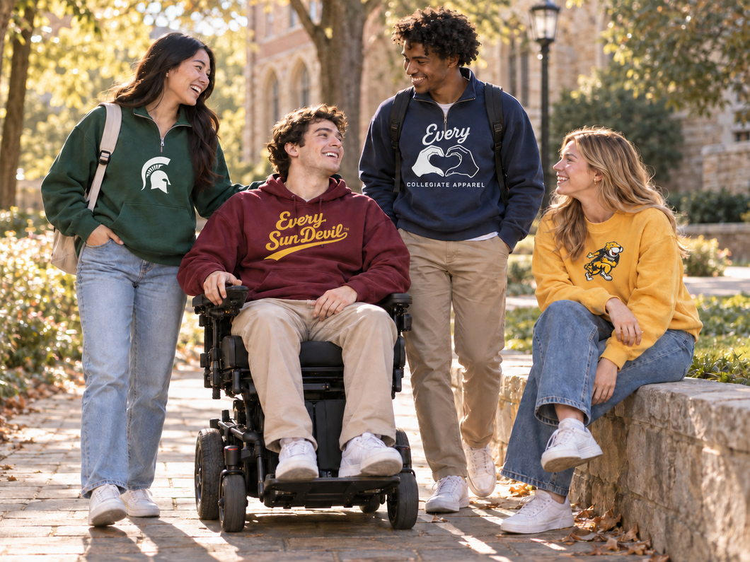 Four friends outdoors on a sunny path, two seated on stone walls, one in a wheelchair, smiling and chatting.