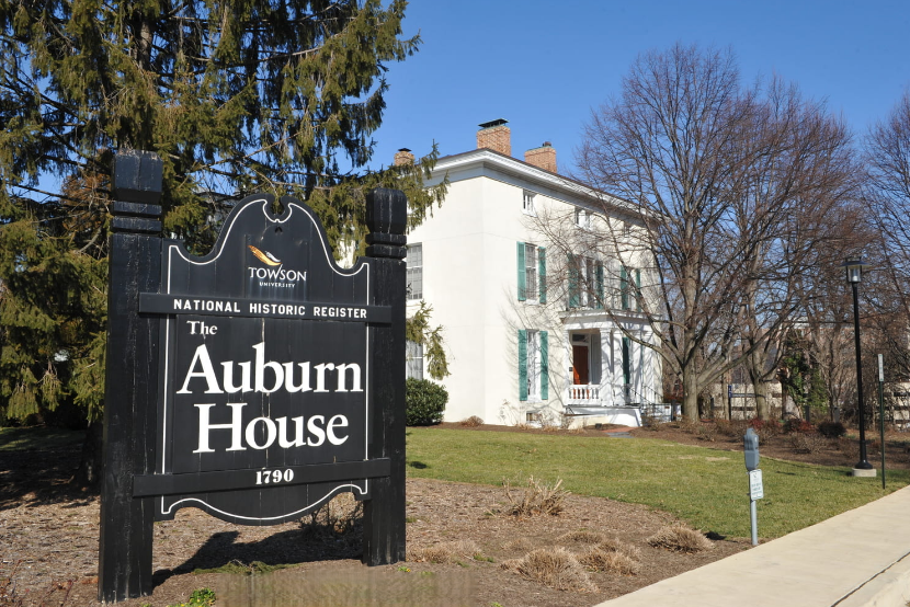 Auburn House historic home with sign, white colonial building and trees on a sunny day