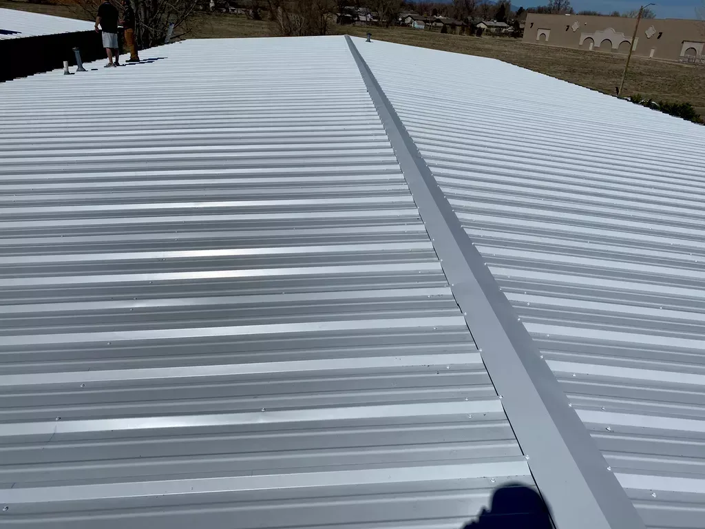 A person is standing on a roof that is covered in snow.