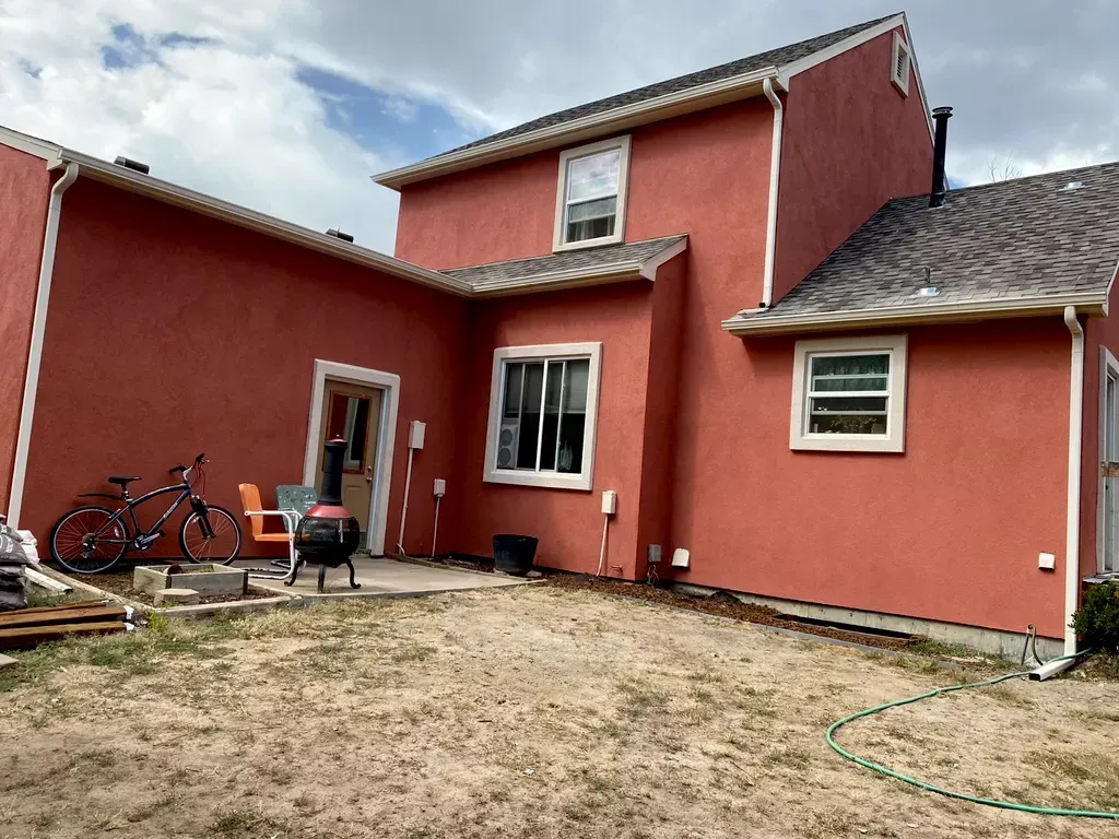 A red house with a bicycle parked in front of it.