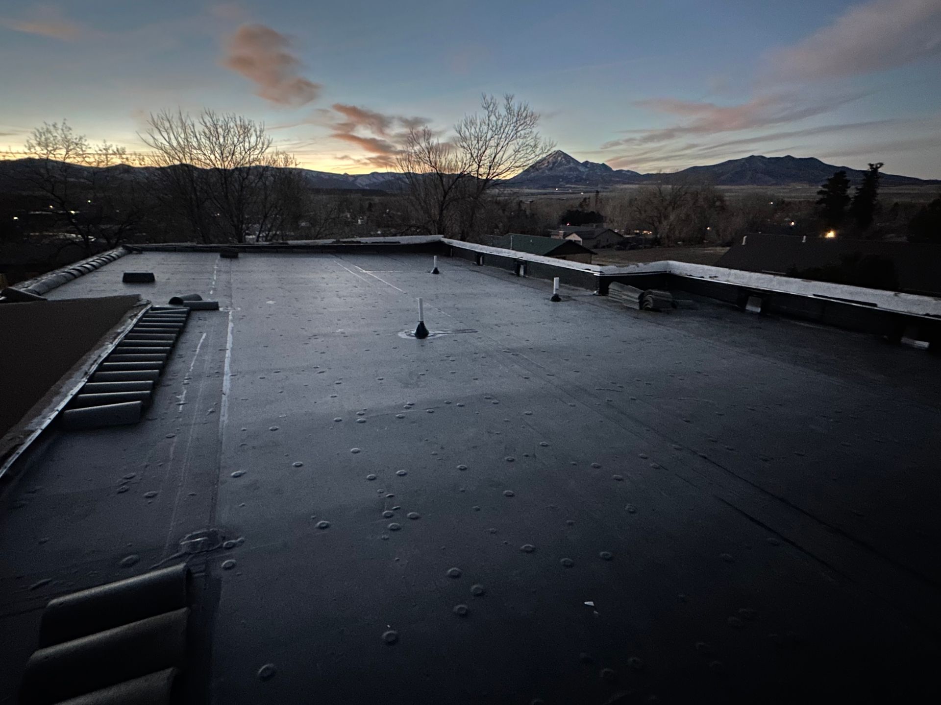 A black roof with a mountain in the background at sunset.
