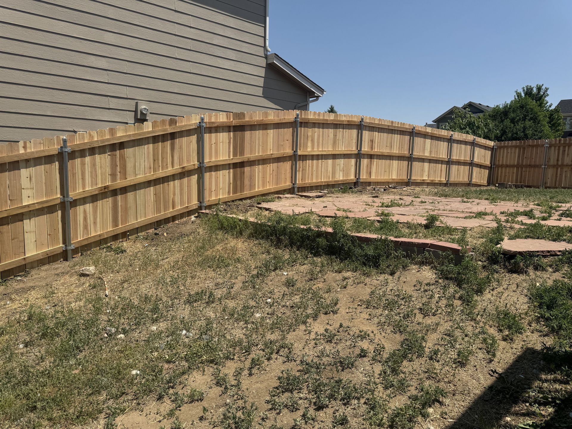 A wooden fence is in the backyard of a house.