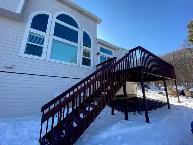 A house with stairs leading up to a deck in the snow