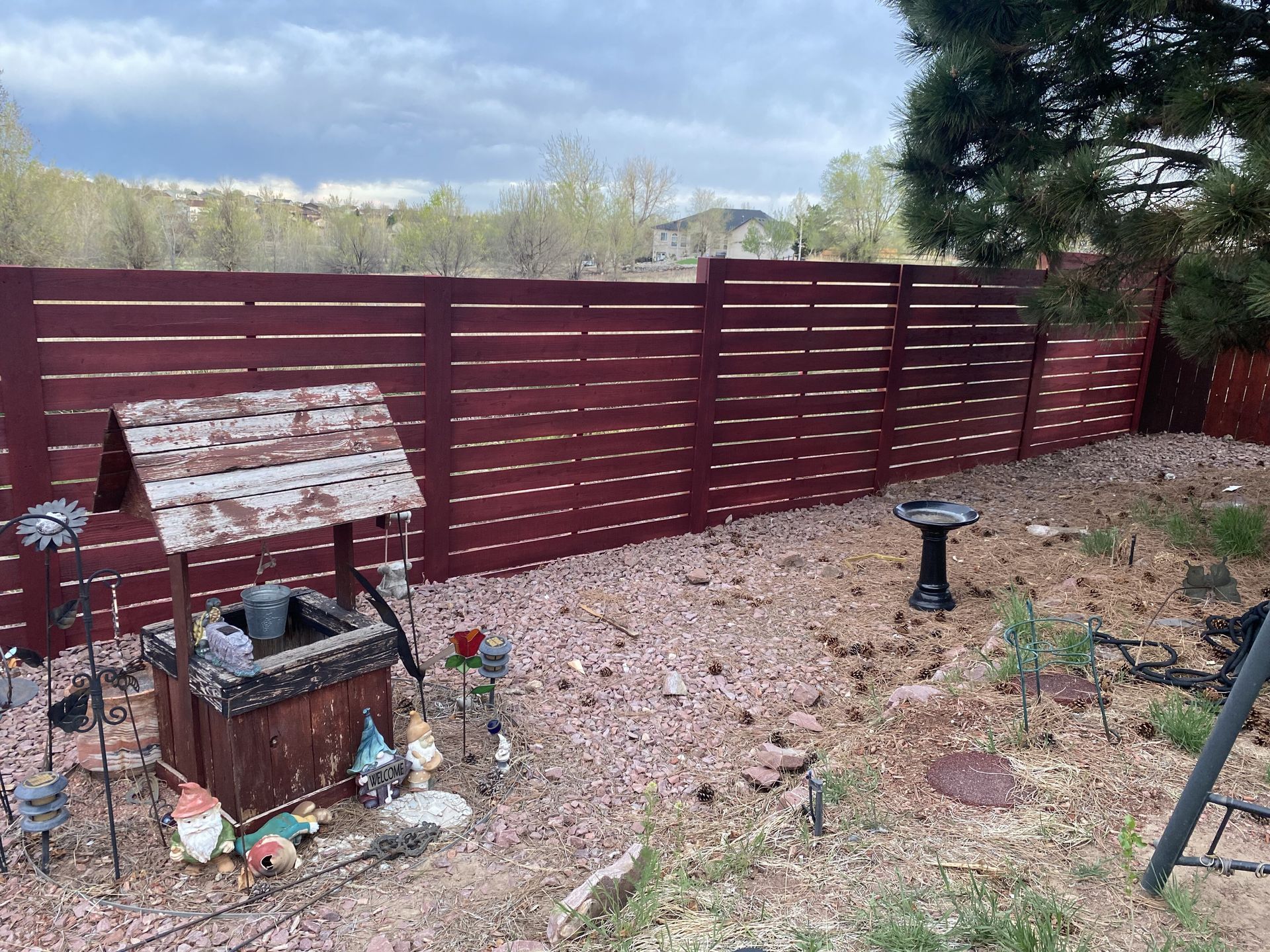 A backyard with a wooden fence and a wishing well.