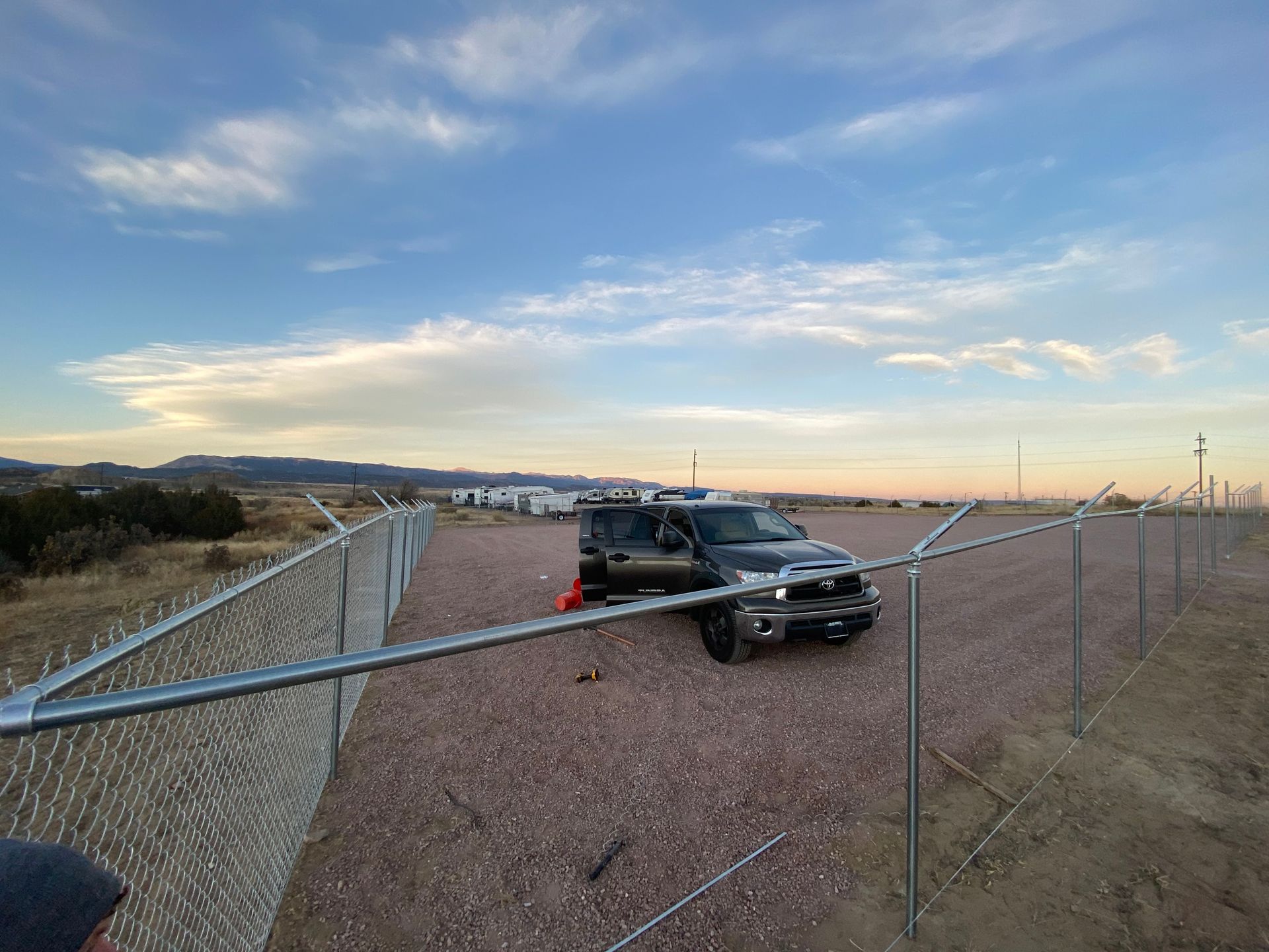 A truck is parked in front of a chain link fence.