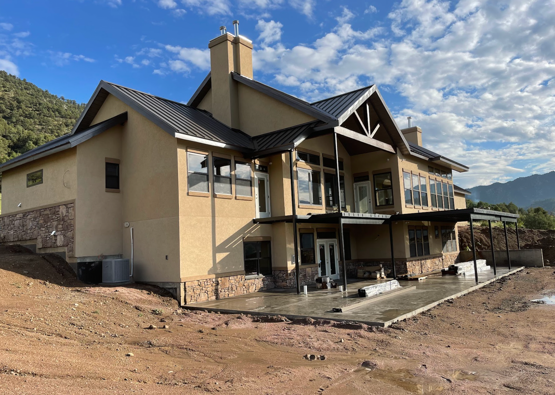 A large house is sitting on top of a dirt hill.