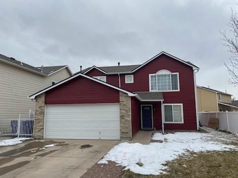 A red house with a white garage door and a snowy yard.