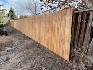 A long wooden fence is sitting in the middle of a dirt field.