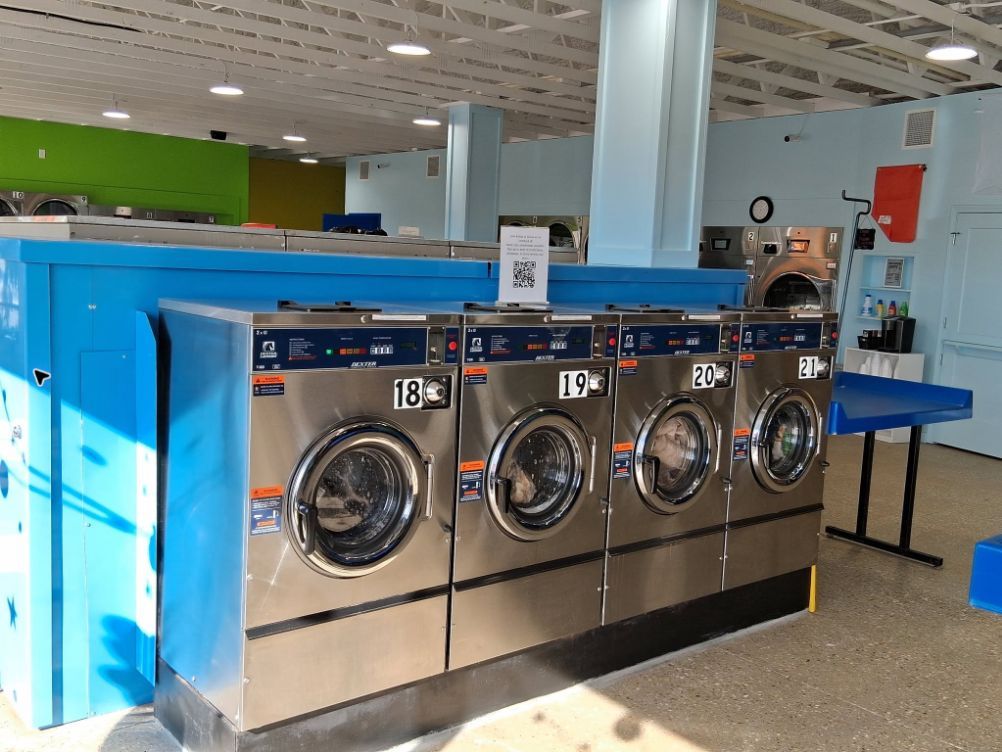 Large-capacity stainless-steel washers inside Sunny Day Laundromat