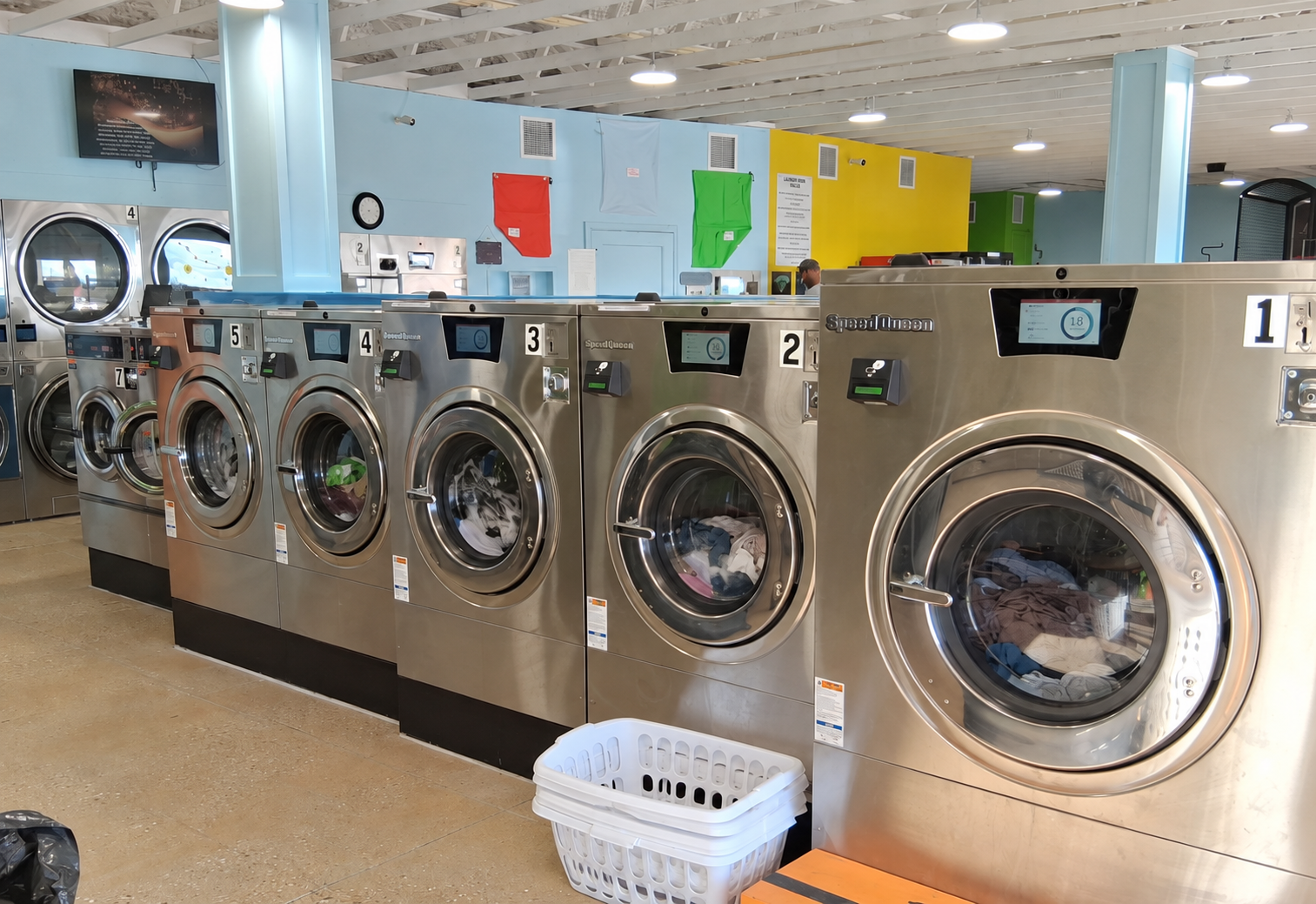 A row of stainless-steel front-loading washers at Sunny Day Laundromat