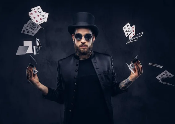A man in a top hat and sunglasses is juggling playing cards.