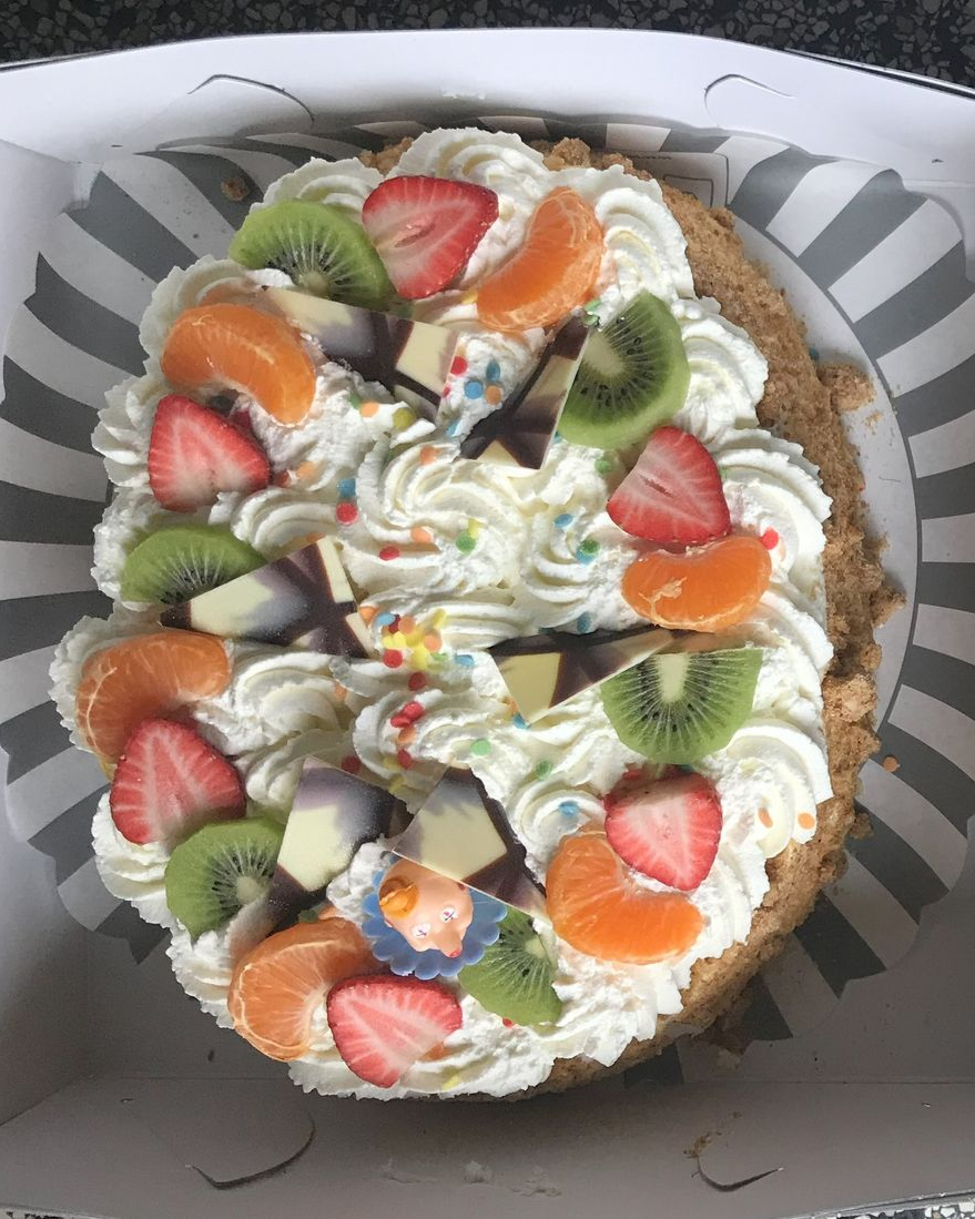 Slagroomtaart met slagroom en fruittopping in een doos.