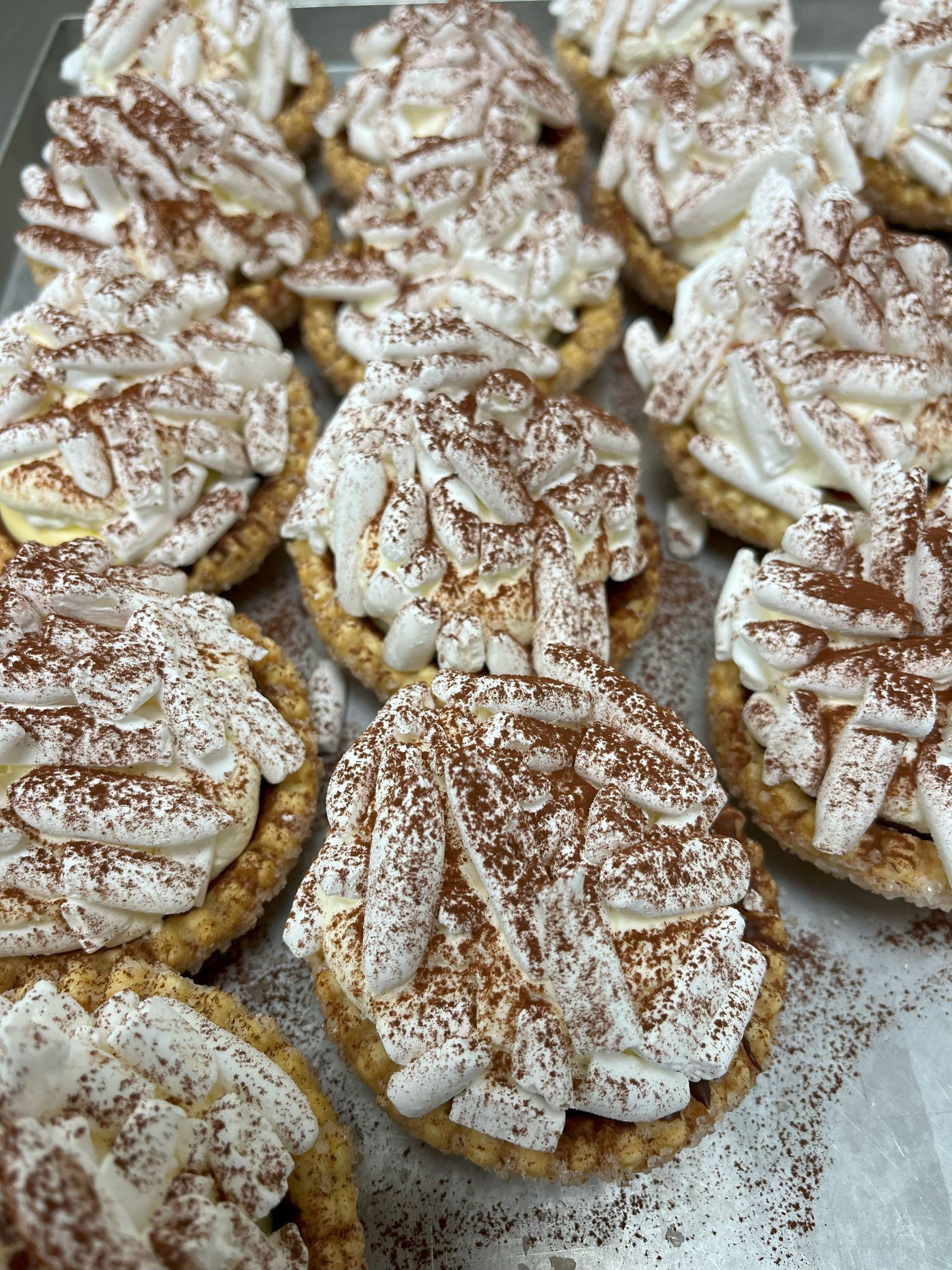 Boerentroef, bedekt met slagroommeringue en bestrooid met cacaopoeder, gerangschikt op een dienblad.