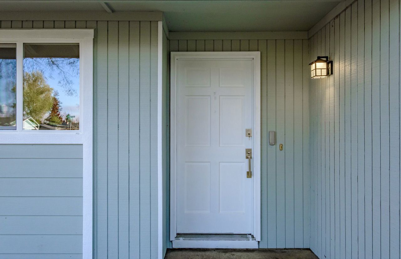 The front door of a house with a white door and a window.