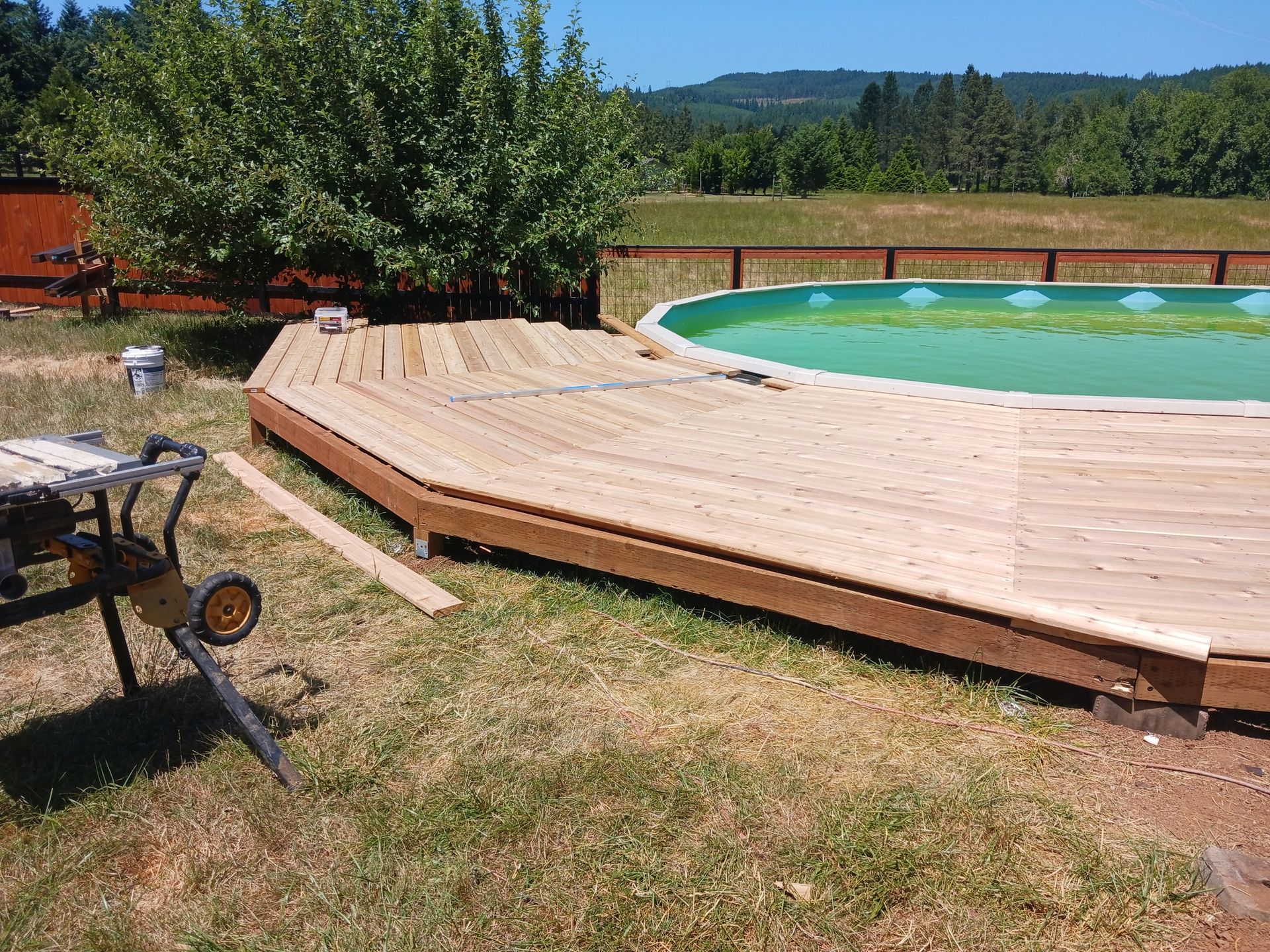 A wooden deck is being built around a swimming pool.