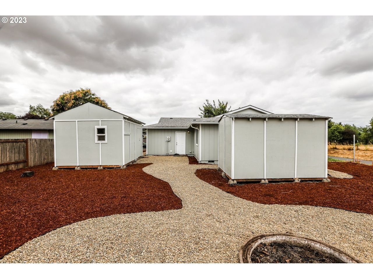There are two sheds in the backyard of a house.