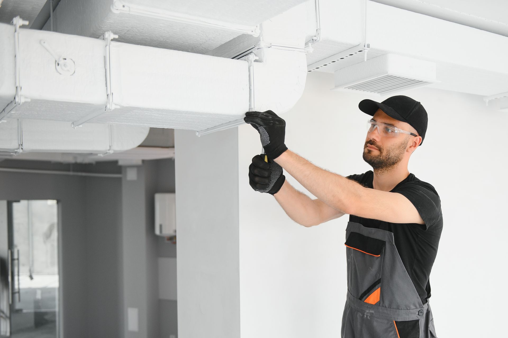 Un homme travaille sur un système de ventilation dans un bâtiment.