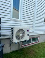 Un grand climatiseur est monté sur le côté d'une maison.