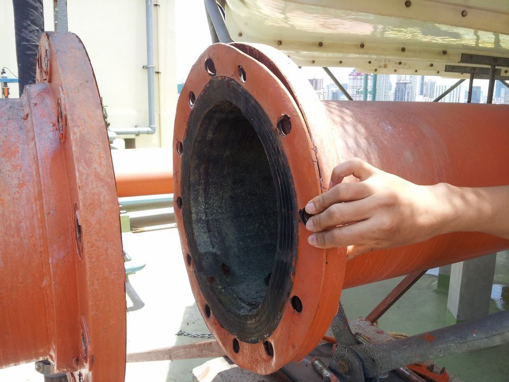 A Close Up Of A Person's Hand On An Orange Pipe — Blackpoly Pipelines in Young, NSW
