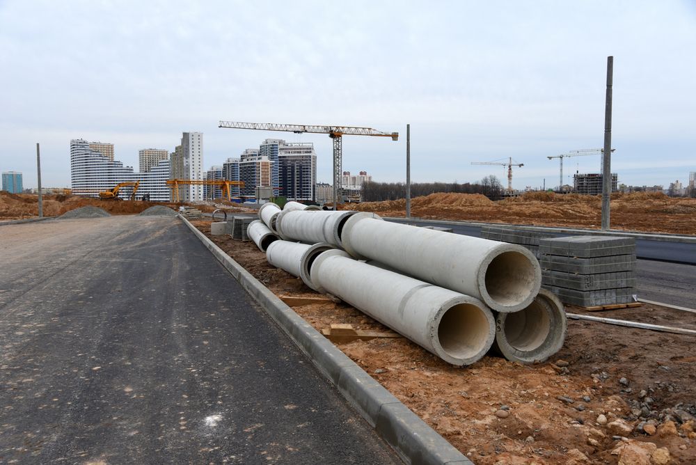 Concrete Pipes Are Stacked On The Side Of A Road At A Construction Site — Blackpoly Pipelines in Bathurst, NSW
