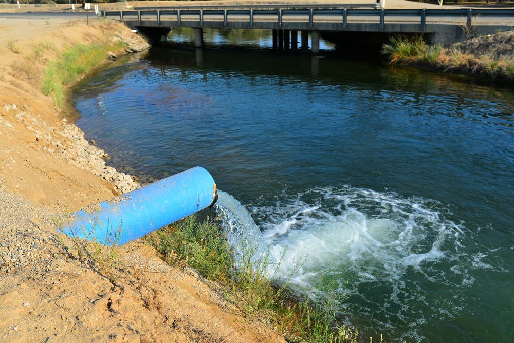 A Blue Pipe Is Pouring Water Into A River — Blackpoly Pipelines in Dubbo, NSW