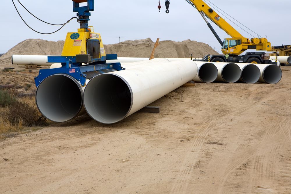 A Crane Is Lifting A Bunch Of Pipes In The Dirt — Blackpoly Pipelines in Cloncurry, QLD